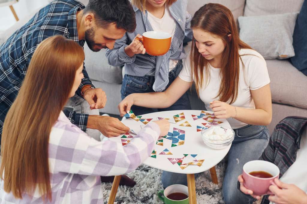 Playing puzzle game. Group of friends have party indoors together
